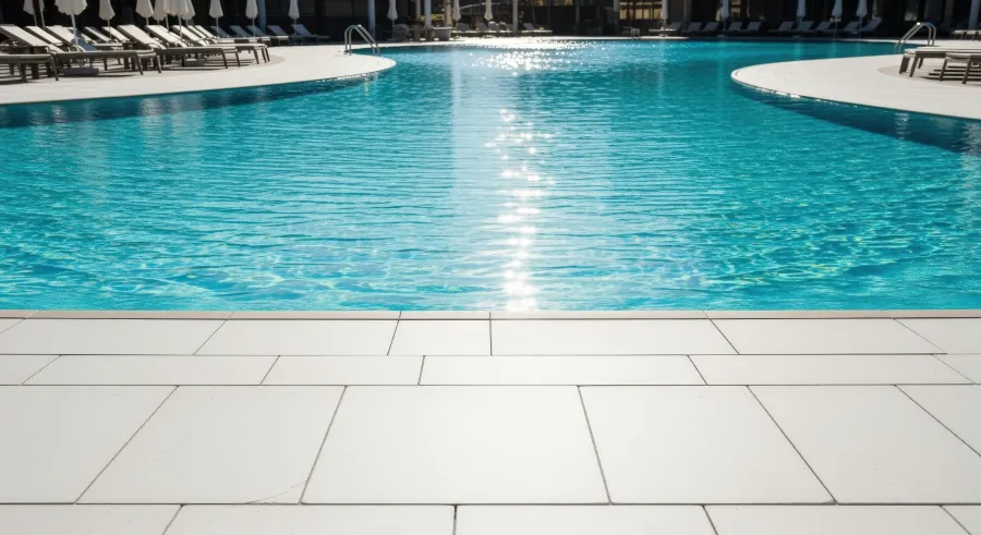 Pool deck outdoor living installation schalimar fl Serene Swimming Pool Scene with Clear Blue Water and White Tile Deck on Sunny Day